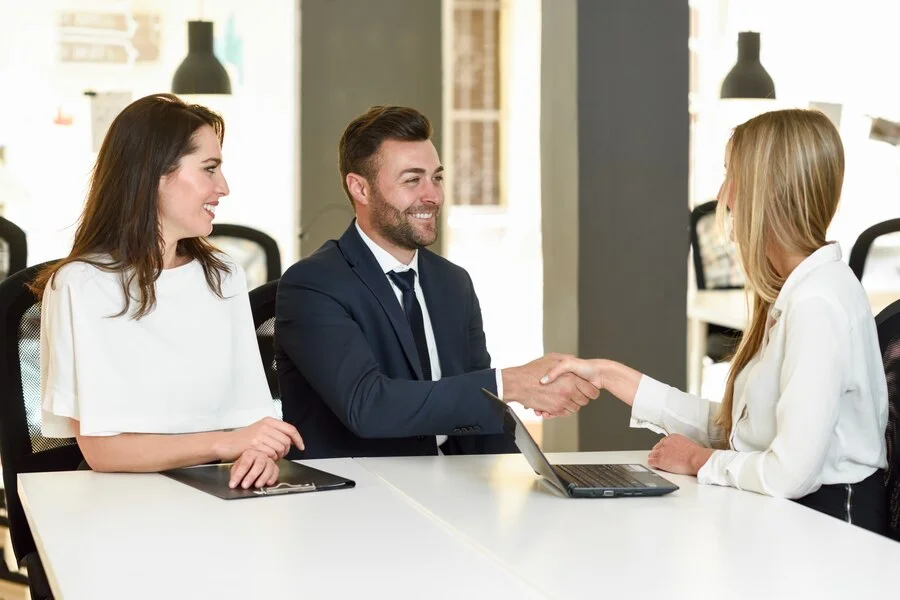 smiling-young-couple-shaking-hands-with-insurance-agent_1139-978